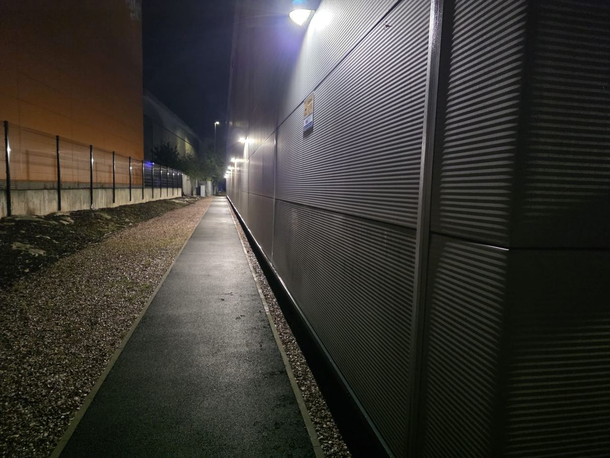 Lit Footpath Beside a Corrugated Wall